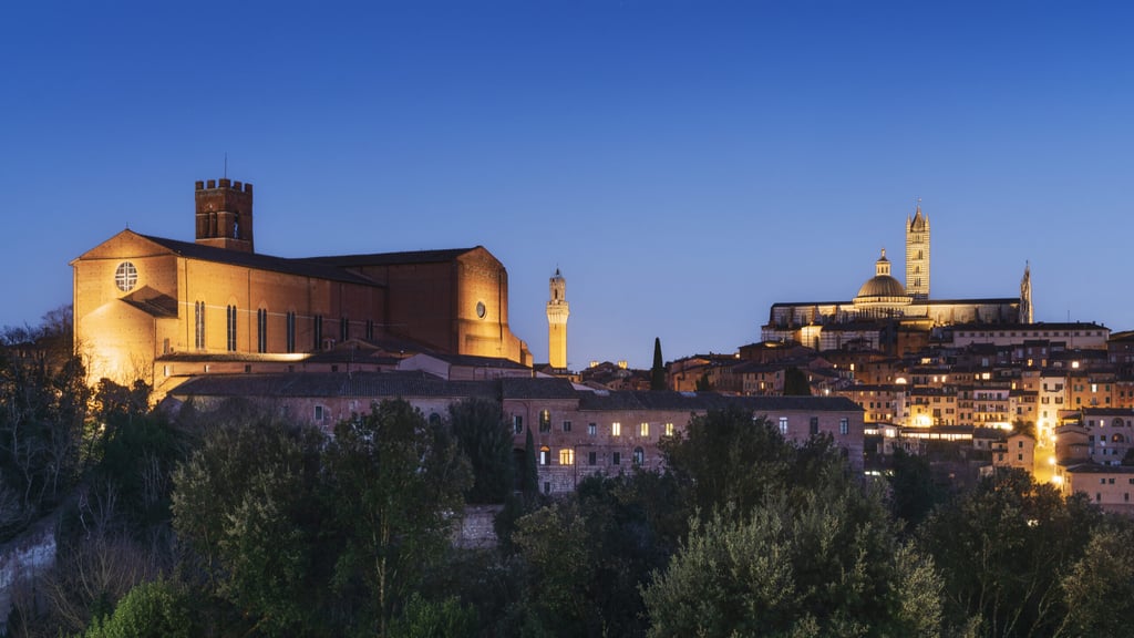 Blue hour over Siena skyline. From the left, the Basilica of San Domenico also known as Basilica Cateriniana, the Mangia tower, and the cathedral also known as Duomo di Siena. Italy