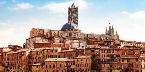 View of building in center of Siena, Italy with Cathedral of Santa Maria Assunta in background