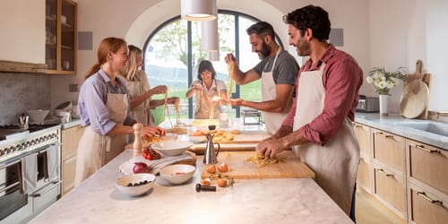 Family enjoying cooking class in farmhouse at Casali di Casole, Tuscany, Italy.