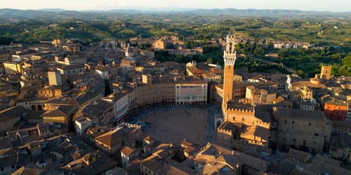 Aerial view of Torre del Mangia (Mangia Tower) in Piazza del Campo (Campo Square) in Siena, Tuscany, Italy. Drone orbit shot at sunset