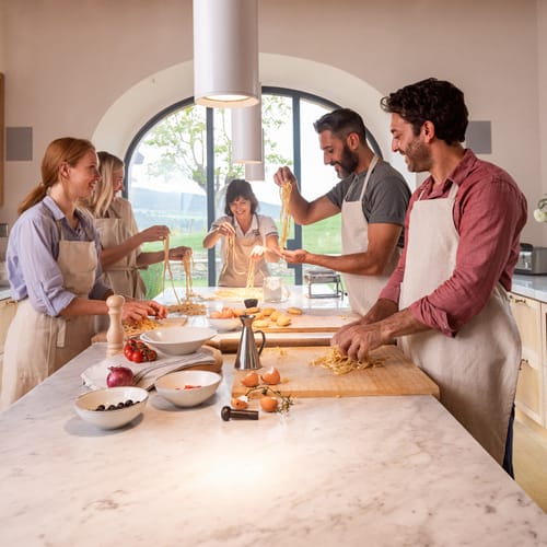 Family enjoying cooking class in farmhouse at Casali di Casole, Tuscany, Italy.