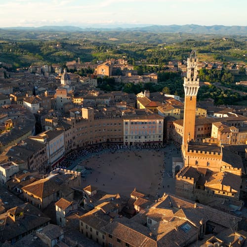 Aerial view of Torre del Mangia (Mangia Tower) in Piazza del Campo (Campo Square) in Siena, Tuscany, Italy. Drone orbit shot at sunset
