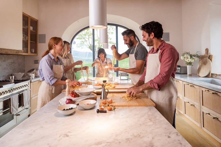 Family enjoying cooking class in farmhouse at Casali di Casole, Tuscany, Italy.